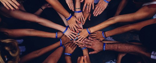 Lots of hands reaching into the middle of a circle